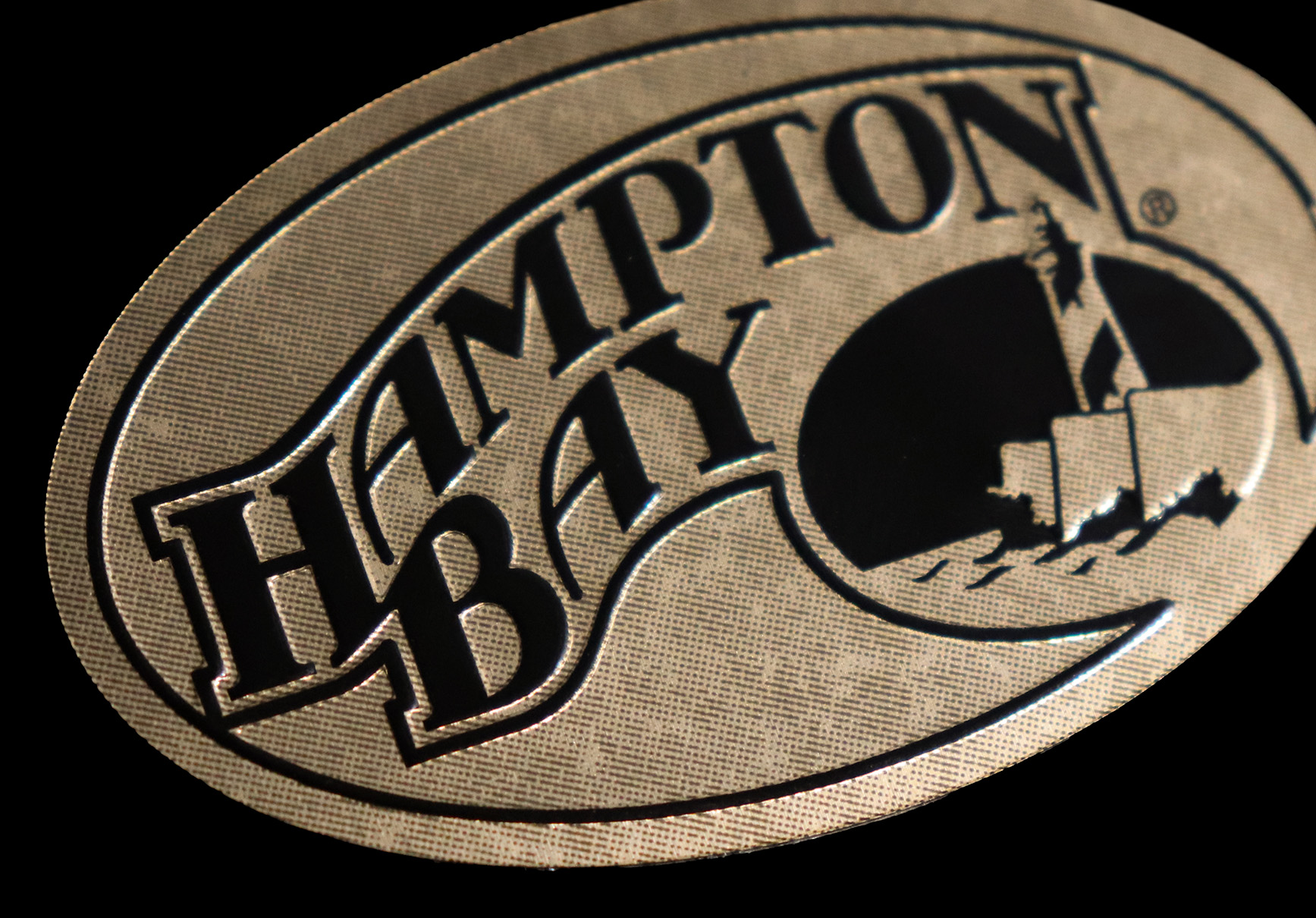 Metal nameplate with a gold tint, patina finish and an emboss